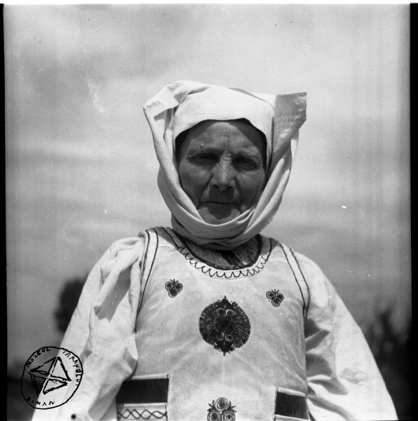 Portret de bătrână (BA-528) - Aurel Bau(c)h, 01 ian 1938 - 31 dec 1947, Transilvania - Femeie din Țara Oltului (sau Țara Făgărașului). Este îmbrăcată în cămașă încrețită la gât și pieptar înfundat cu broderie, iar pe cap poartă o „căiță cu pomeselnic” - foto preluat de pe www.facebook.com/@MuzeulTaranului